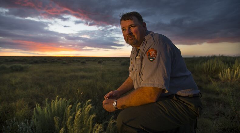 Shawn Gillette, chief of interpretation, National Park Service, Sand Creek Massacre National Historic Site, kneels in the grass where the historic massacre happened at dawn June 30, 2016, near Eads, Colo. (Allen J. Schaben/Los Angeles Times/TNS)