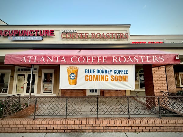The exterior of a shop with a marquee that reads Atlanta Coffee Roasters, which has closed, and a banner hanging below it that says Coming Soon: Blue Donkey Coffee.