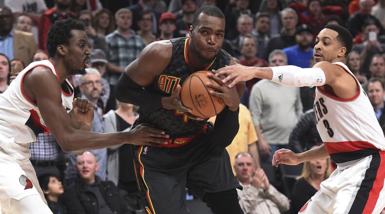 Atlanta Hawks forward Paul Millsap drives to the basket on Portland Trail Blazers forward Al-Farouq Aminu and guard C.J. McCollum in the second half of an NBA basketball game in Portland, Ore., Monday, Feb 13, 2017. Atlanta won in overtime 109-104. (AP Photo/Steve Dykes)