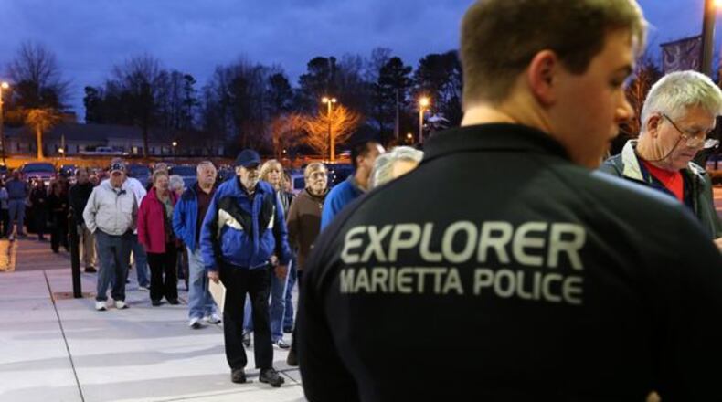 Brent Gunkle, with the Marietta Police Explorers, watches the door as hundreds of people arrive for an active shooter seminar put on by the police department Wednesday evening at Marietta High School. Police say 800 people registered for the seminar and at least 200 more tried to register. Ben Gray / bgray@ajc.com