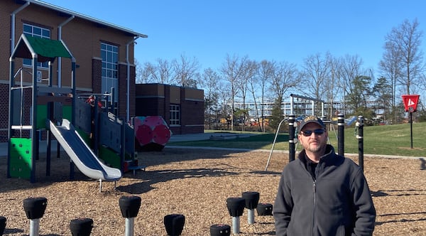 Mike Phillips, on the playground of his son's school in Prince William County, says that he's boxed in by data centers, one under construction next to the school and two others in various approval stages. (Zachary Hansen/AJC)