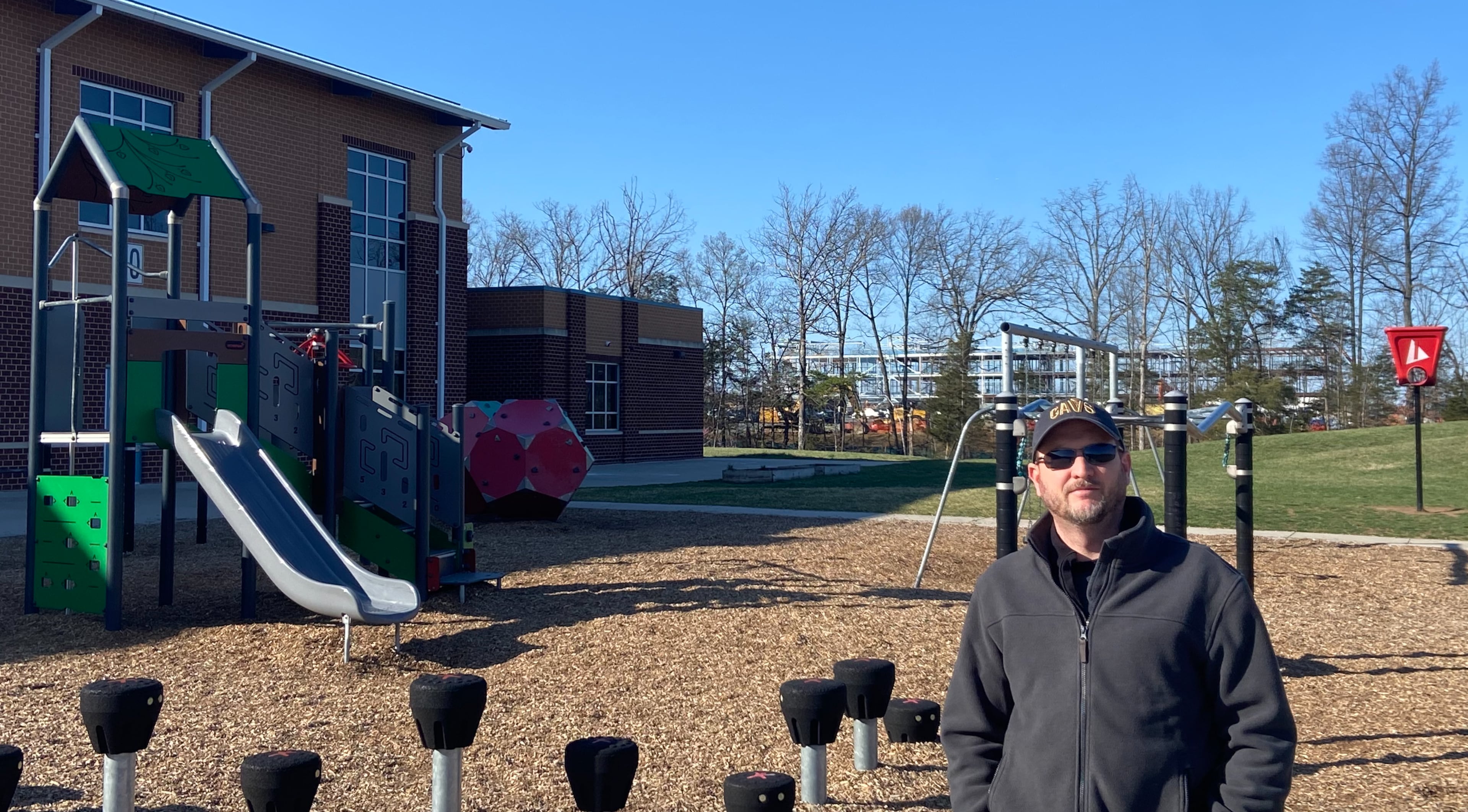 Mike Phillips, on the playground of his son's school in Prince William County, says that he's boxed in by data centers, one under construction next to the school and two others in various approval stages. (Zachary Hansen/AJC)