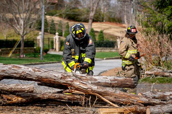 Firefighters cut and remove a tree that had fallen Sunday on Harris Trail in northwest Atlanta. (Ben Hendren for the Atlanta Journal-Constitution).