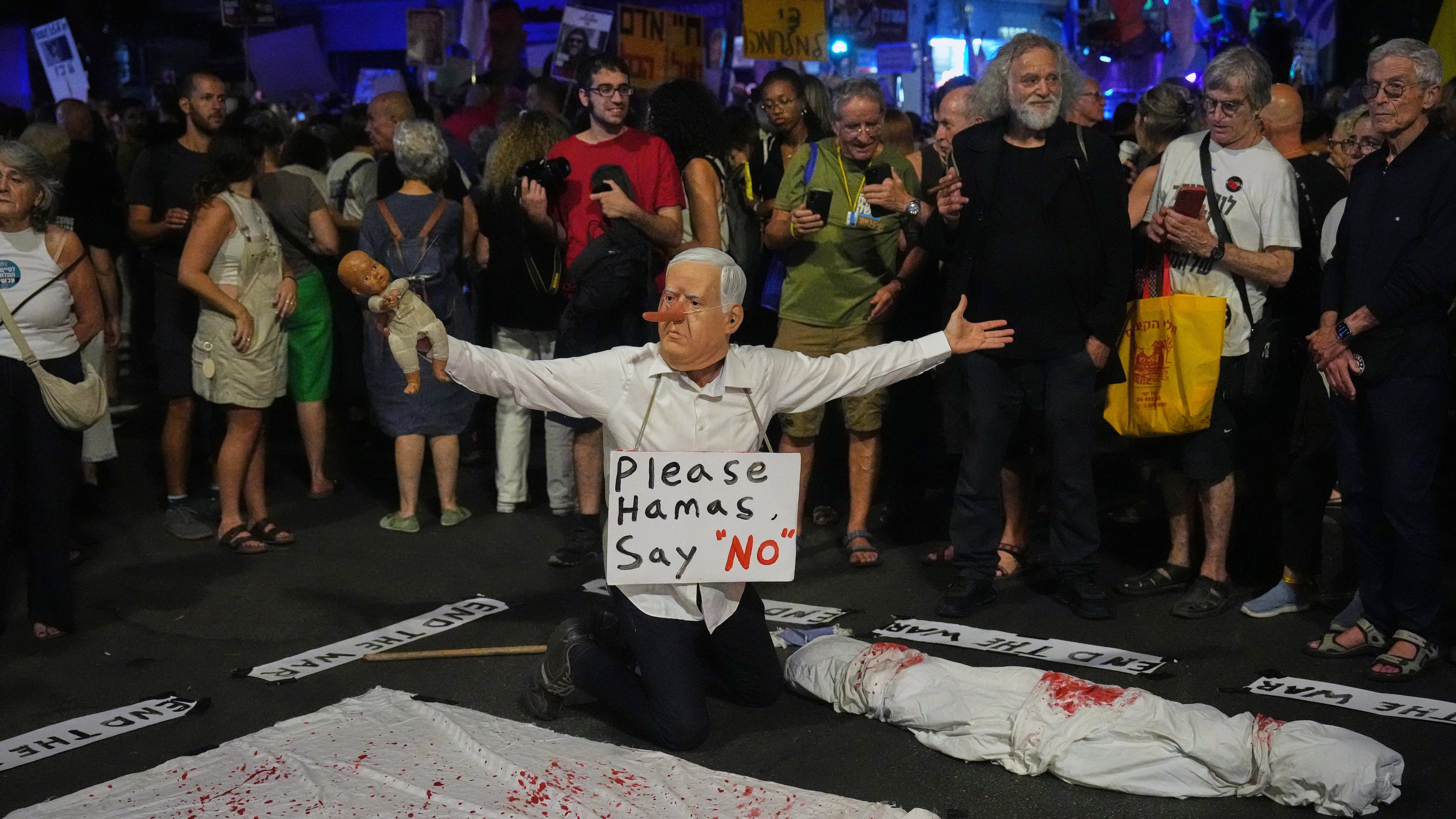 A demonstrator wears a mask depicting Israeli Prime Minister Benjamin Netanyahu during a protest calling for the immediate release of all hostages held by Hamas in the Gaza Strip and an end to the ongoing war, in Tel Aviv, Israel, Tuesday, Sept. 30, 2025, (AP Photo/Ariel Schalit)
