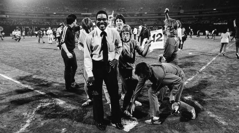 A member of Atlanta-Fulton County Stadium security guards home plate as fans celebrate the Braves' 12th straight win in 1982. (Louie Favorite / AJC staff)