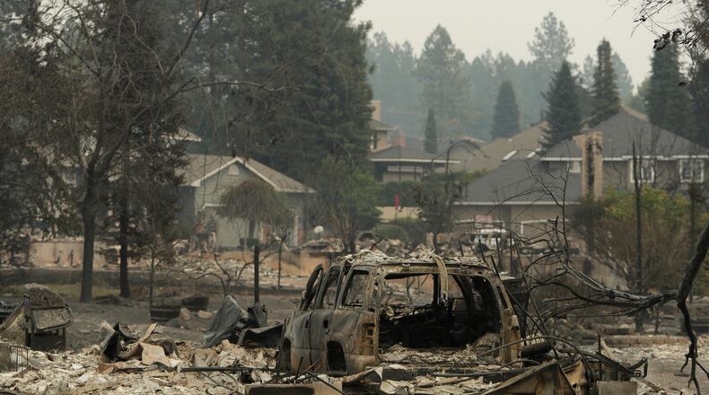A vehicle and structure are burned on N. Skyline Dr. due to a wildfire, Sunday, Aug. 2, 2026, in Spokane, Wash. (AP Photo/Young Kwak)