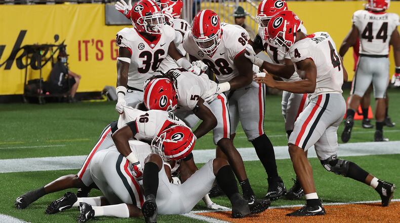 Teammates pile on Georgia defensive back Christopher Smith in the end zone after he intercepted a pass intended for Clemson wide receiver Justyn Ross and returned it for a touchdown during the second quarter Saturday, Sept 4, 2021, in Charlotte, N.C. The Bulldogs took a 7-0 lead. (Curtis Compton / Curtis.Compton@ajc.com)