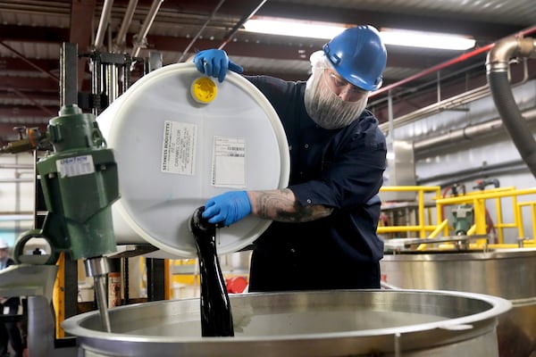 Caleb Whorl pours a container of caramel coloring into a vat to be mixed before packaging at Sensient Technologies Corp., a color additive manufacturing company, in St. Louis, on Wednesday, April 2, 2025. (AP Photo/Jeff Roberson)