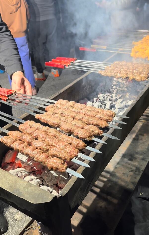 Skewers of meat cooking over a charcoal grill.