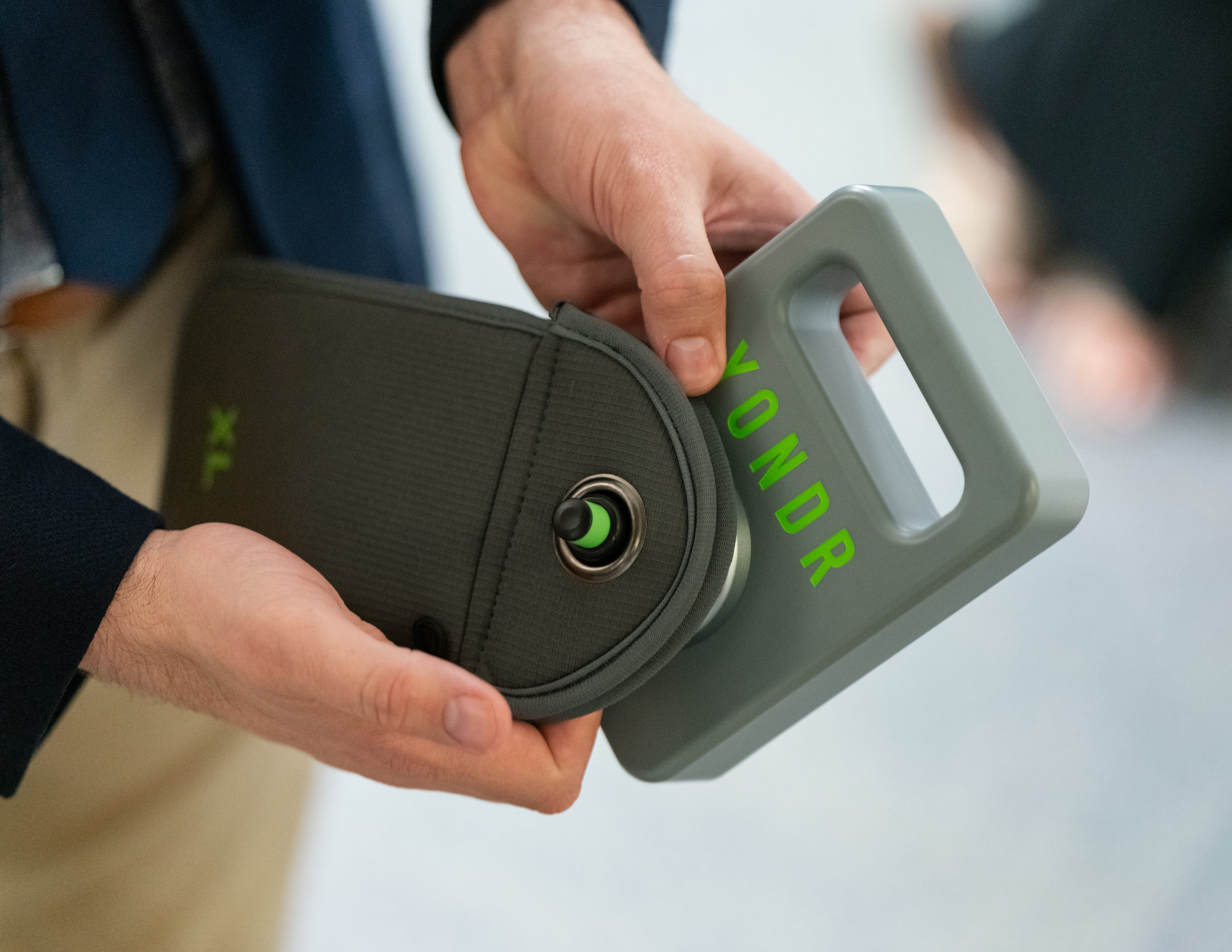 A school administration employee demonstrates the use of a lockable pouch for phone, to be used in the schools. The Marietta city school board unanimously passed a ban on cellphones for middle school students. Tuesday, May 18, 2024. (Ben Hendren for the AJC)