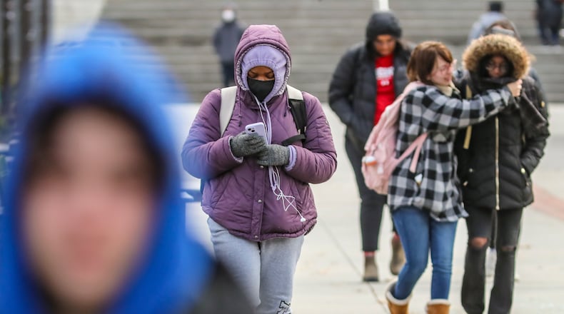 Renee Barnes,19, (center) a first-year student from Lawrenceville listens to music as Rebecca Thompson, 18, (right) a first-year student from Athens and Danielle Cofield, 19, (far-right) a first-year student from College Park bundled up against the bitter cold on the Tech Walkway on the Georgia Tech campus on Tuesday morning. Temperatures fell into the 20s and 30s as a cold front swept across the area. It’s winter’s first blast of dangerously cold arctic air, with temps running nearly 20 degrees below normal, according to the National Weather Service. (John Spink / John.Spink@ajc.com)