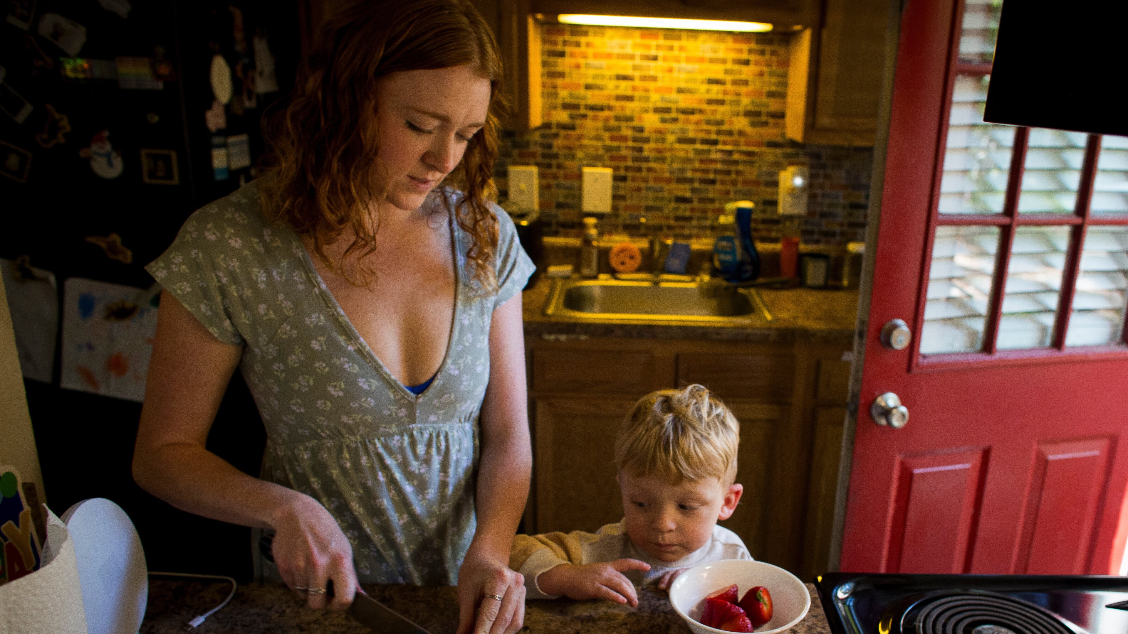 Taylor Moyer slices strawberries as her youngest son, Bradley, helps put the sliced fruit into a bowl while at home in the kitchen, Sunday, Oct. 5, 2025, in Virginia Beach, Va. (AP Photo/John Clark)