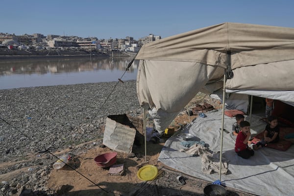 Children sit in their tent at a camp for displaced Palestinians, located near a rainwater collection reservoir that has been contaminated by sewage and garbage following the Israeli air and ground operations in Gaza City, Friday, July 18, 2025. (AP Photo/Jehad Alshrafi)