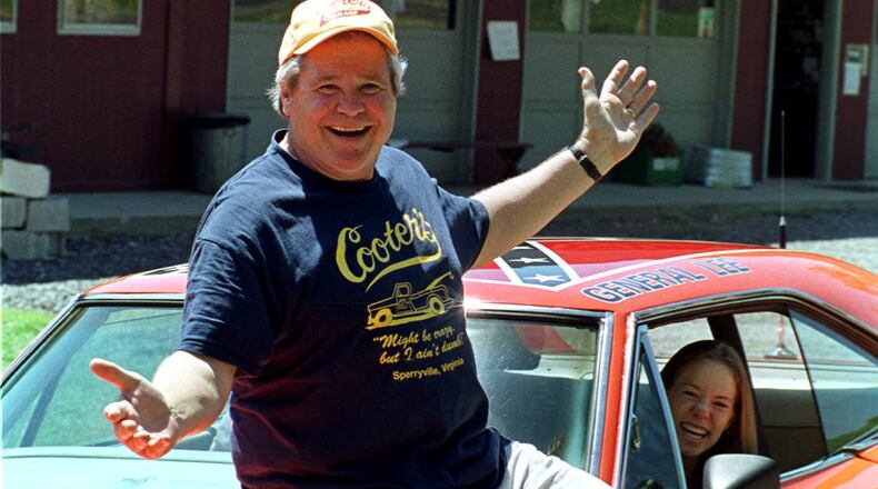 FILE - Cooter, actor Ben Jones, sits atop one of the 229 hotrods, named the General Lee, used in the show "Dukes of Hazzard" as ecstatic fan, Aliceson Johnson, of Charlottesville, Va., sits in the drivers seat in front of his store in Sperryville, Va., Tuesday, Aug. 10, 1999. (AP Photo/Steve Helber, File)