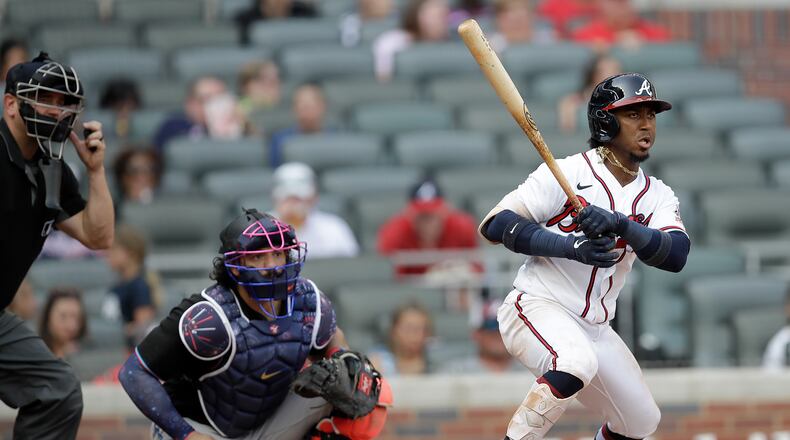 Atlanta Braves' Ozzie Albies, right, watches his RBI-single against the Miami Marlins during the fifth inning of a baseball game Saturday, July 3, 2021, in Atlanta. (AP Photo/Ben Margot)