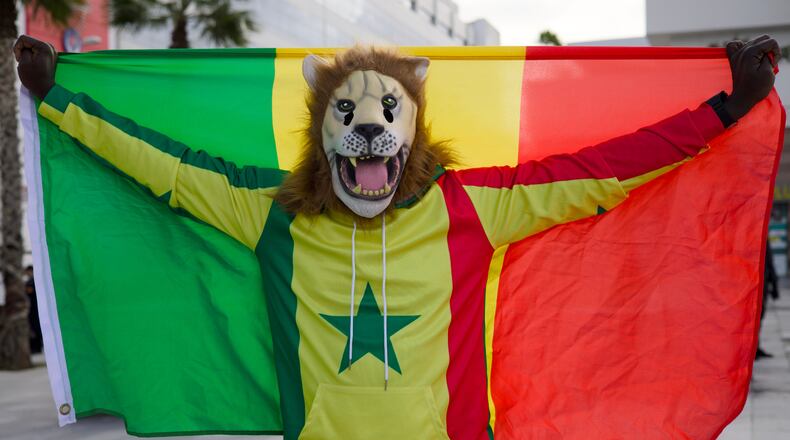 Senegal fan Pape, dressed as a lion, holds the Senegal flag at the Africa Cup of Nations in Tangier, Morocco, Dec. 23, 2025. (AP Photo/Ciaran Fahey)