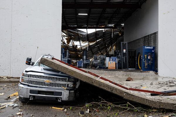 A smashed truck sits under a section of collapsed warehouse wall after violent storms and tornadoes tore through the area on Thursday, April 3, 2025, in Jeffersontown, Ky. (AP Photo/Jon Cherry)