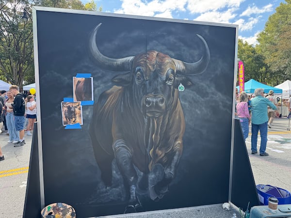 Douglas' Lee Mobley has yet to finish this latex paint mural of a bull at Chalktoberfest in Marietta on Saturday, Oct. 11, 2025. (Caleb Groves/ AJC)