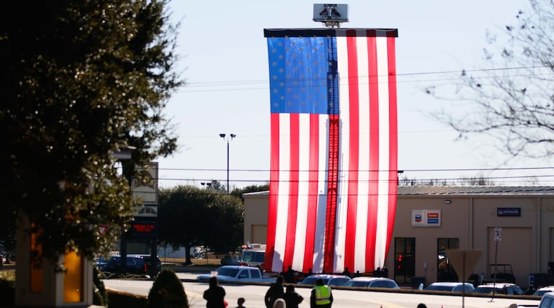 Sumter County firefighters display a large American flag outside the Phoebe Sumter Medical Center in Americus on Saturday, Jan. 4, 2025, just moments before the motorcade carrying former President Jimmy Carter’s family arrived. (Miguel Martinez/AJC)