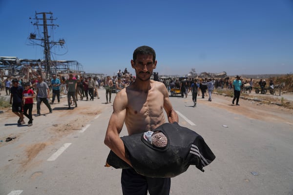 A Palestinian man carries food in his T-shirt after receiving aid from the Gaza Humanitarian Foundation, a U.S.-backed organization approved by Israel, in Khan Younis, southern Gaza Strip, on Thursday, May 29, 2025. (AP Photo/Abdel Kareem Hana)