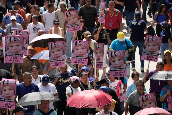 Pro-government supporters hold up signs with the image of Maikelys Espinoza, a 2-year-old in US custody whose parents were deported separately, at a May Day rally in Caracas, Venezuela, Thursday, May 1, 2025. (AP Photo/Ariana Cubillos)