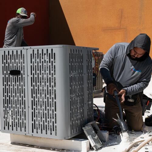 FILE - Sonel Telemaque, left, wipes sweat from his brow while installing a new air conditioning unit alongside Brian Hermosillo during record-breaking heat, March 19, 2026, in Tempe, Ariz. (AP Photo/Caitlin O'Hara, File)