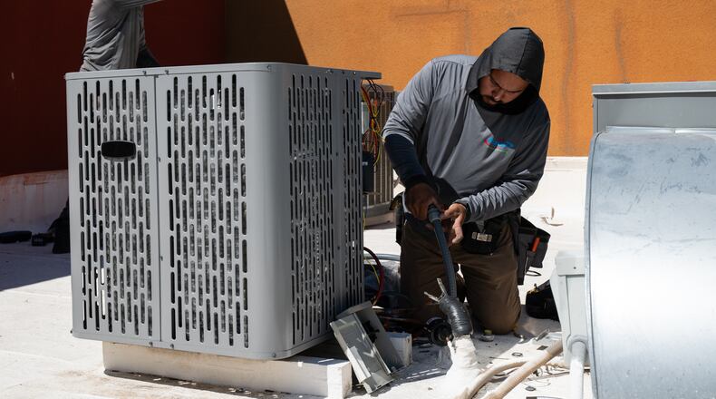 FILE - Sonel Telemaque, left, wipes sweat from his brow while installing a new air conditioning unit alongside Brian Hermosillo during record-breaking heat, March 19, 2026, in Tempe, Ariz. (AP Photo/Caitlin O'Hara, File)