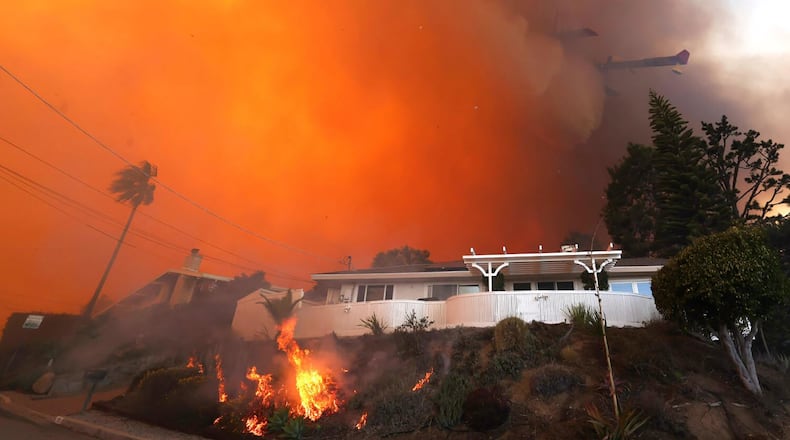 A firefighting plane makes a drop on a burning home from the Palisades fire in Pacific Palisades, California, which quickly consumed more than 1,200 acres of vegetation on Jan. 7, 2025, pushed by gusting Santa Ana winds. (Brian van der Brug/Los Angeles Times/TNS)