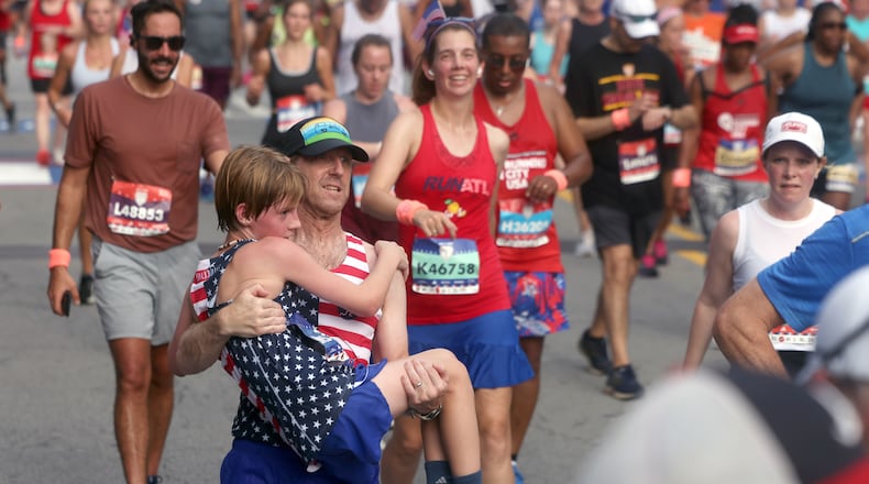Young runner gets assist at the finish of the 55th running of the Atlanta Journal-Constitution Peachtree Road Race in Atlanta on Thursday, July 4, 2024.   (Jason Getz / AJC)
