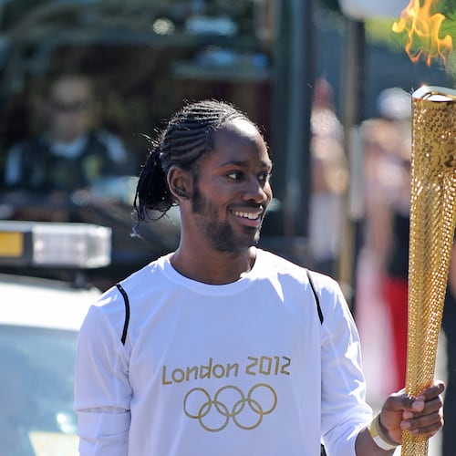 Torchbearer Jason Arday carries the Olympic Flame on the Torch Relay leg between Sutton and Merton, in London, July 23, 2012. (Joe Giddens/LOCOG/PA via AP)