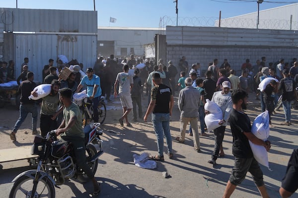 Palestinians carry bags of flour after storming a U.N. World Food Program warehouse in Zawaida, Central Gaza Strip, on Wednesday, May 28, 2025. (AP Photo/Abdel Kareem Hana)