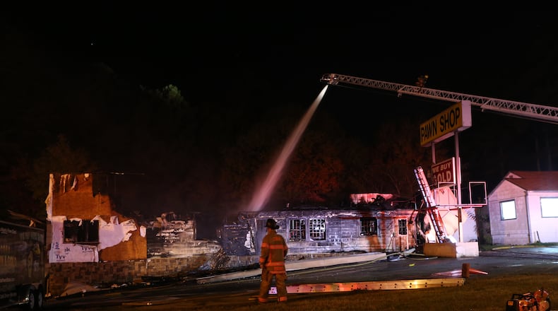 Cobb County firefighters put out hot spots after a fire at CobbGold and Jewelry on South Cobb Drive on Monday night. (BEN GRAY / BGRAY@AJC.COM)
