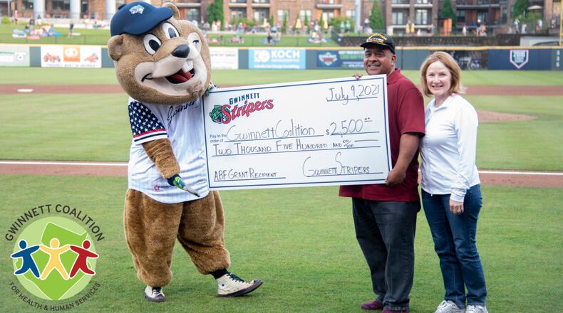 Chopper, the Gwinnett Stripers' mascot, delivers a $2,500 check to representatives of the Gwinnett Coalition during a July 9 home game. (Courtesy of Gwinnett Stripers)
