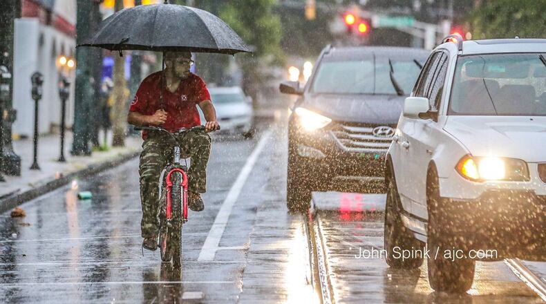Ravi Sing tried to stay dry Tuesday morning as he waited for the light to change on Auburn Avenue and Hilliard Street in downtown Atlanta. JOHN SPINK / JSPINK@AJC.COM