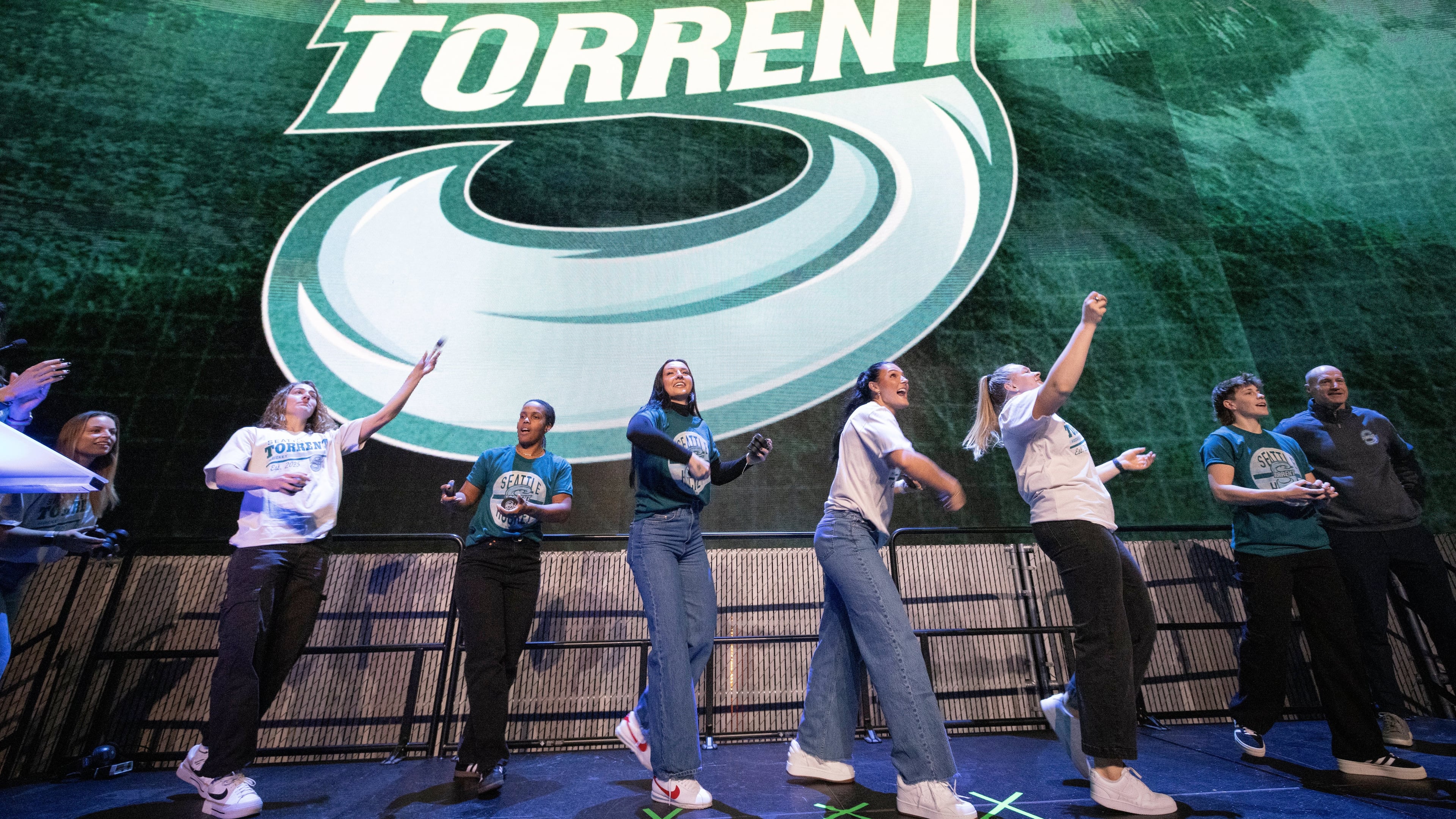 Seattle Torrent members toss gifts to the crowd during an event unveiling the PWHL hockey team's new logo and name, Thursday, Nov. 6, 2025, in Seattle. (Ken Lambert/The Seattle Times via AP)
