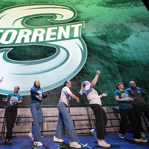 Seattle Torrent members toss gifts to the crowd during an event unveiling the PWHL hockey team's new logo and name, Thursday, Nov. 6, 2025, in Seattle. (Ken Lambert/The Seattle Times via AP)