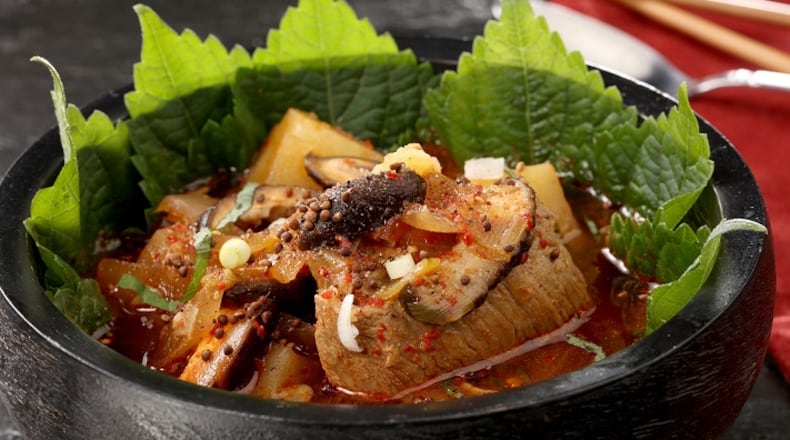 Vivid perilla leaves provide a vibrant background for a bowl of gamjatang, a Korean soup of potatoes, pork bones and plenty of chile-based spices. (Michael Tercha/Chicago Tribune/TNS)