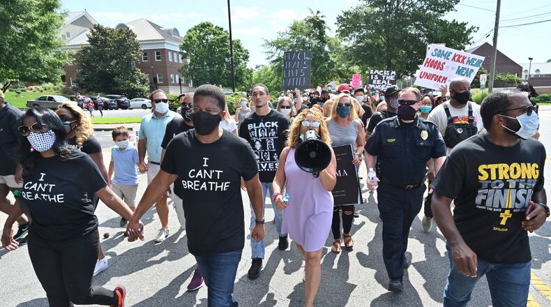 Pastor Lee Jenkins with his wife, Martica, from left, Democratic Congresswoman Lucy McBath (with megaphone)and Roswell Police Chief James Conroy joined the peaceful Solidarity March in downtown Roswell on June 13. McBath's opponent in November, Republican Karen Handel, is using video from the march in an ad trying to portray the congresswoman as anti-police. (Hyosub Shin / Hyosub.Shin@ajc.com)