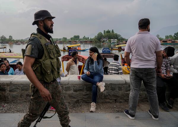 An Indian tourist woman talk to her cell phone as Jammu and Kashmir Special Operation Group (SOG) personnel patrol at a Dal Lake in Srinagar, Indian controlled Kashmir,Tuesday, April. 22, 2025. (AP Photo/Mukhtar Khan)