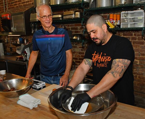 231220 Atlanta, Ga: Mike Smith (left) gets a brief lesson on this morning’s volunteer duty, sweet potato peeling and straining using a tamis (strainer) and plastic paddle, from chef de cuisine Jake Pollitz of Staplehouse just before it opens. (CHRIS HUNT FOR THE ATLANTA JOURNAL-CONSTITUTION)