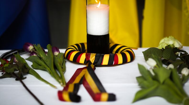 After attacks in Brussels, a candle wrapped in a ribbon in the colors of the Belgium national flag and flowers are placed on a table inside the Belgium Embassy in Berlin, Germany, Tuesday, March 22, 2016. (AP Photo/Markus Schreiber)