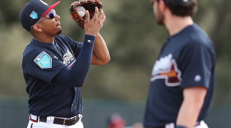 Johan Camargo catches a fly ball with Dansby Swanson looking on.
