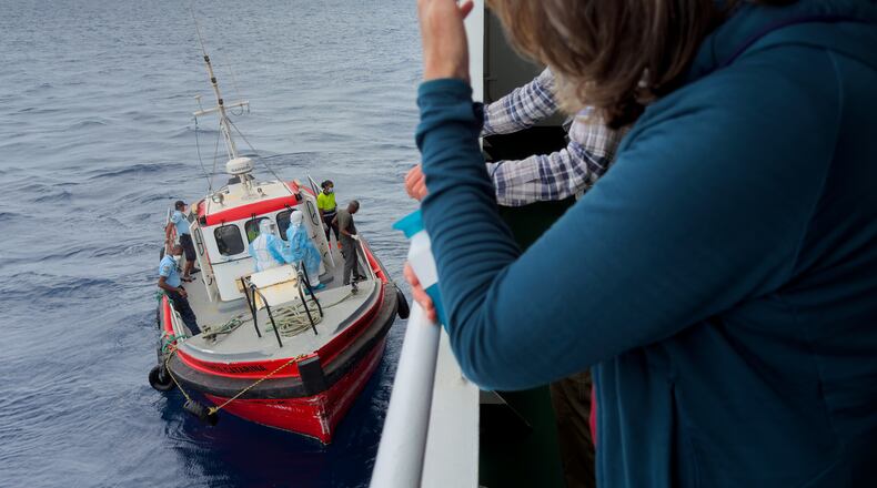 Passengers on the the hantavirus-stricken cruise ship, MV Hondius, watch epidemiologists board the boat in Praia, during their voyage to Spain's port of Tenerife, May 6, 2026. (AP Photo)