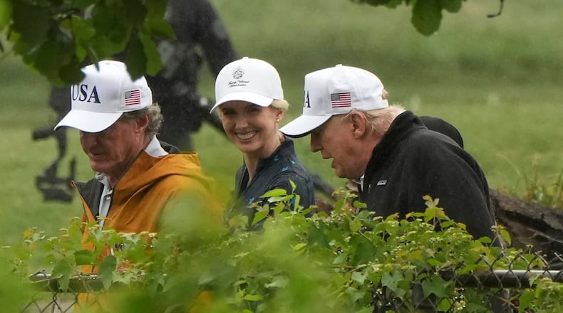 Interior Secretary Doug Burgum (left), White House aide Natalie Harp and President Donald Trump walk during a tour of the East Potomac Park golf course in June. (Mark Schiefelbein/AP)