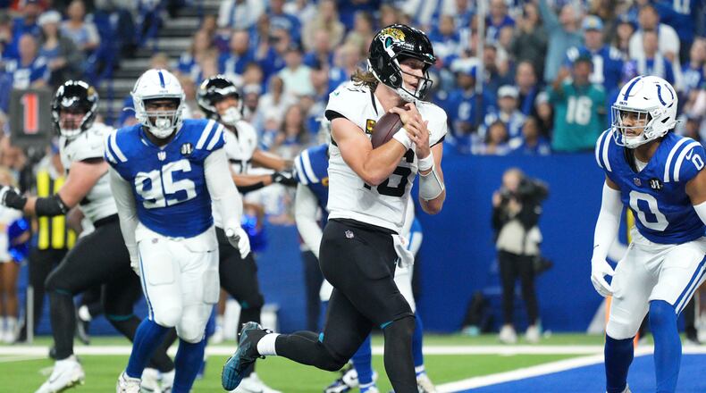 Jacksonville Jaguars quarterback Trevor Lawrence scores past Indianapolis Colts defensive tackle Adetomiwa Adebawore (95) and safety Camryn Bynum (0) during the second half of an NFL football game Sunday, Dec. 28, 2025, in Indianapolis. (AP Photo/AJ Mast)