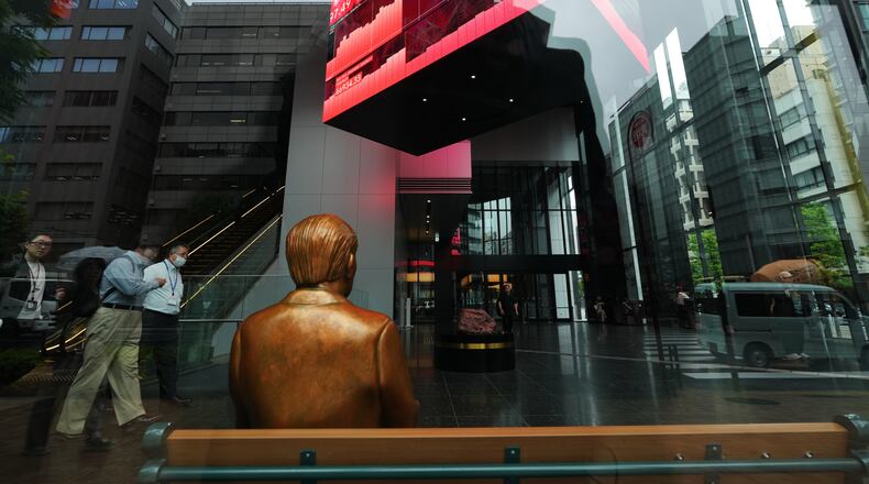 A statue is placed on a bench near monitors showing Japan's Nikkei 225 index, hanging in a business building in Tokyo, Thursday, June 18, 2026. (AP Photo/Hiro Komae)
