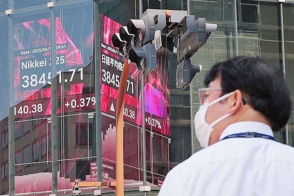 A person walks in front of an electronic stock board showing Japan's Nikkei index at a securities firm Tuesday, June 17, 2025, in Tokyo. (AP Photo/Eugene Hoshiko)