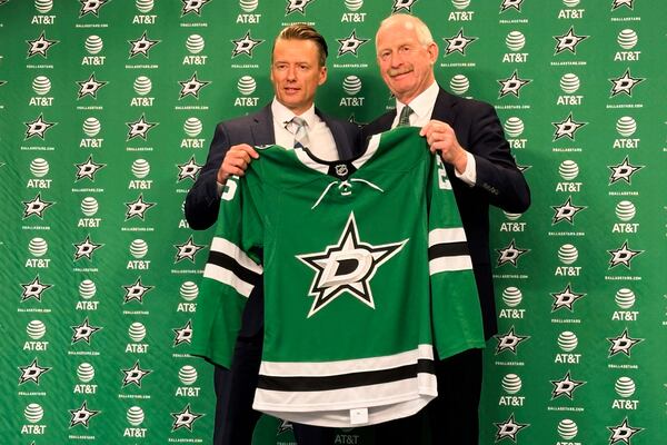 Dallas Stars new head coach Glen Gulutzan, left, and general manager Jim Nill hold up a team jersey after Gulutzan was introduced during an NHL hockey news conference, Wednesday, July 2, 2025, at the American Airlines Center in Dallas. (AP Photo/Stephen Hawkins)