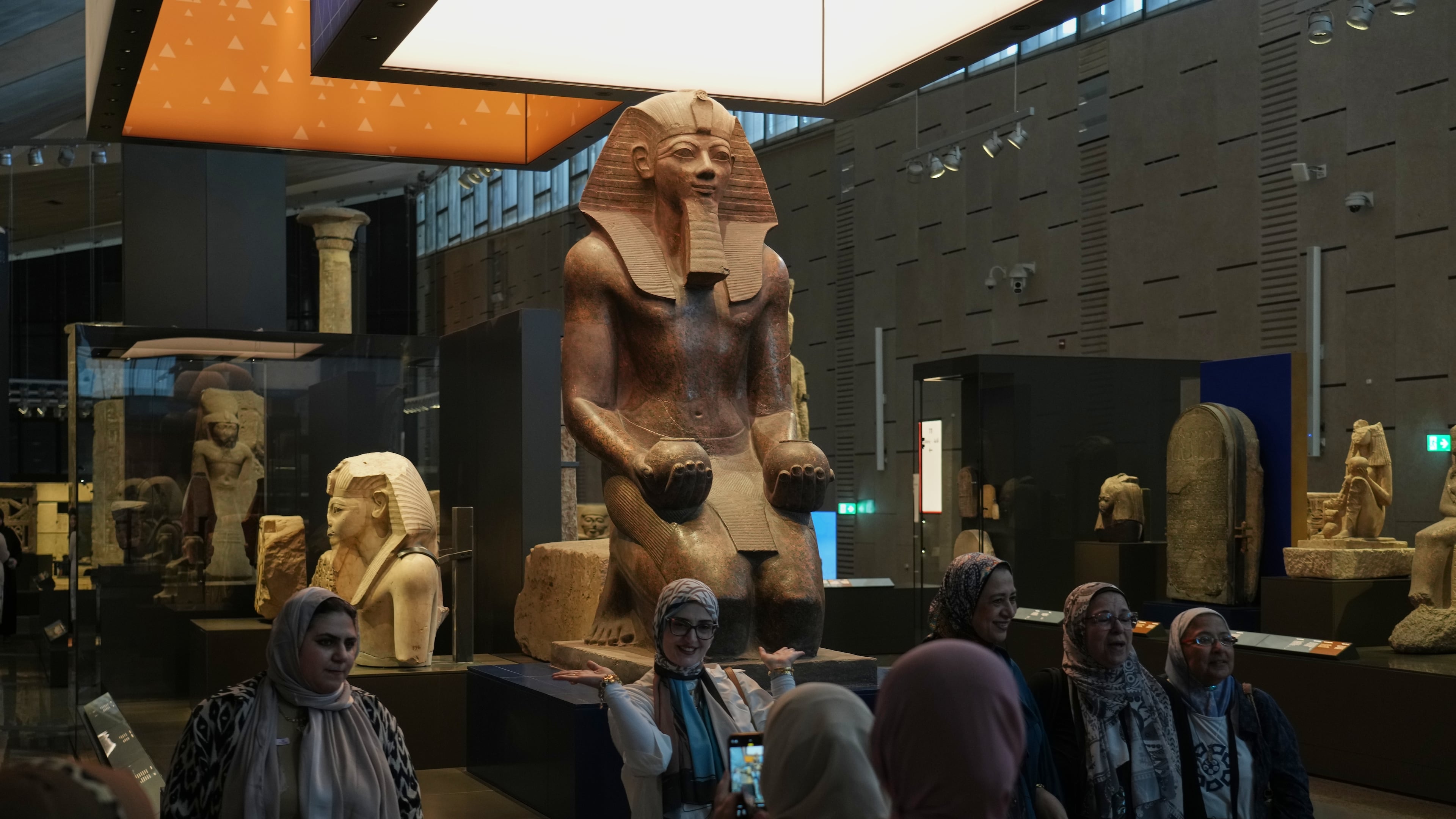 Visitors pose for a group photo under Hatshepsut statue, at the Grand Egyptian Museum in Giza, Egypt, Friday, May 23, 2025. (AP Photo/Amr Nabil)