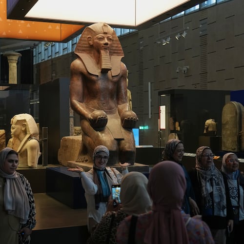 Visitors pose for a group photo under Hatshepsut statue, at the Grand Egyptian Museum in Giza, Egypt, Friday, May 23, 2025. (AP Photo/Amr Nabil)